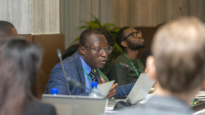 Man speaks into table microphone at conference in Nigeria